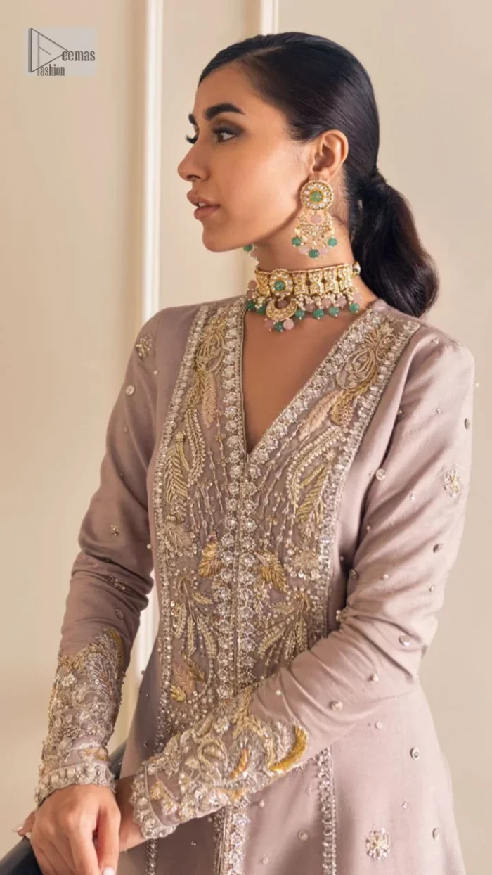 Feel the magic of the party in this splendid article! The ideal front open gown in tea rose colour is heavily hand embellished with floral branches and botanical motifs. It has an embroidered border on the front and back. The V shape neckline is adorned with silver and golden embroidery. It is further prominent with tilla,dabka, kora, Kundan, crystals, stones and the intricate detailing of Zardozi to make this masterpiece lovely and charming. Further, the full sleeves are decorated with tiny floral motifs and sequins spray. It is paired with trousers that complete the party wear look.