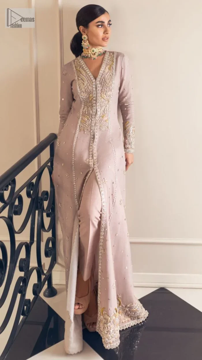 Feel the magic of the party in this splendid article! The ideal front open gown in tea rose colour is heavily hand embellished with floral branches and botanical motifs. It has an embroidered border on the front and back. The V shape neckline is adorned with silver and golden embroidery. It is further prominent with tilla,dabka, kora, Kundan, crystals, stones and the intricate detailing of Zardozi to make this masterpiece lovely and charming. Further, the full sleeves are decorated with tiny floral motifs and sequins spray. It is paired with trousers that complete the party wear look.