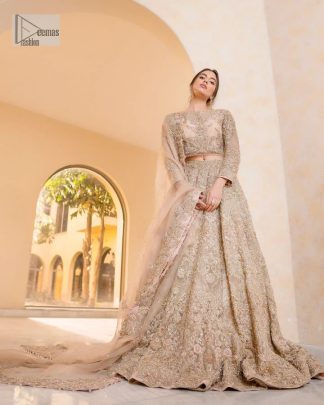It features a softgalm-inspired look that redefines elegance.  An elegant rhyme to tradition, the attractive and beautiful walima wear lehnga choli creates aesthetical magic with its eye-catching ivory colour. The blouse shines with embellishments and an amalgamation of floral patterns in silver and golden colours. It is further intensified with tilla, dabka, kora, Kundan and the real magic of Zardozi. The boat shape neckline makes this charming. In addition to this, the floral patterns on full sleeves make this masterpiece more lovely. The perfect outfit is paired with a flared lehenga which is heavily ornamented with handsome embroidery. Complete this with an organza dupatta which is adorned with a four-sided embellished border and sprayed with tiny floral motifs and sequins all over to make your day fresh and bright.