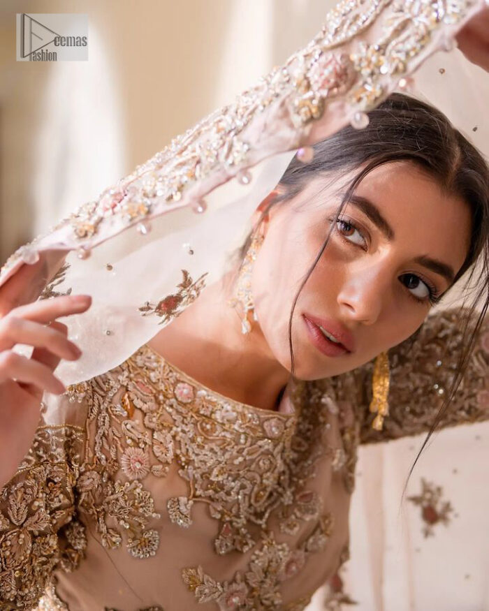 It features a softgalm-inspired look that redefines elegance.  An elegant rhyme to tradition, the attractive and beautiful walima wear lehnga choli creates aesthetical magic with its eye-catching ivory colour. The blouse shines with embellishments and an amalgamation of floral patterns in silver and golden colours. It is further intensified with tilla, dabka, kora, Kundan and the real magic of Zardozi. The boat shape neckline makes this charming. In addition to this, the floral patterns on full sleeves make this masterpiece more lovely. The perfect outfit is paired with a flared lehenga which is heavily ornamented with handsome embroidery. Complete this with an organza dupatta which is adorned with a four-sided embellished border and sprayed with tiny floral motifs and sequins all over to make your day fresh and bright.