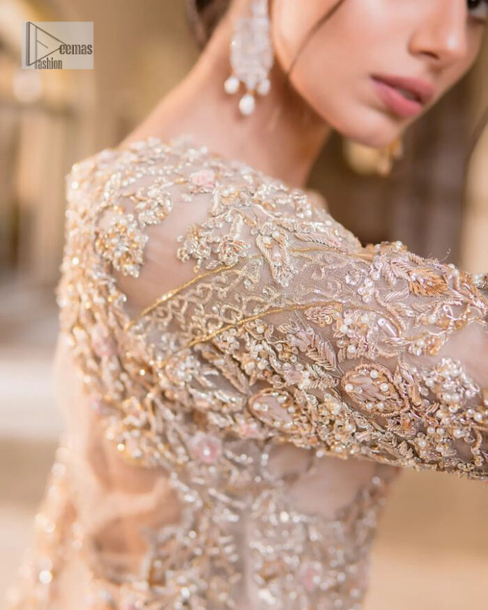 It features a softgalm-inspired look that redefines elegance.  An elegant rhyme to tradition, the attractive and beautiful walima wear lehnga choli creates aesthetical magic with its eye-catching ivory colour. The blouse shines with embellishments and an amalgamation of floral patterns in silver and golden colours. It is further intensified with tilla, dabka, kora, Kundan and the real magic of Zardozi. The boat shape neckline makes this charming. In addition to this, the floral patterns on full sleeves make this masterpiece more lovely. The perfect outfit is paired with a flared lehenga which is heavily ornamented with handsome embroidery. Complete this with an organza dupatta which is adorned with a four-sided embellished border and sprayed with tiny floral motifs and sequins all over to make your day fresh and bright.