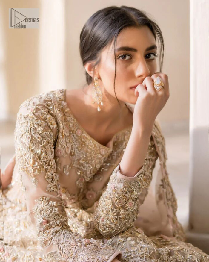 It features a softgalm-inspired look that redefines elegance.  An elegant rhyme to tradition, the attractive and beautiful walima wear lehnga choli creates aesthetical magic with its eye-catching ivory colour. The blouse shines with embellishments and an amalgamation of floral patterns in silver and golden colours. It is further intensified with tilla, dabka, kora, Kundan and the real magic of Zardozi. The boat shape neckline makes this charming. In addition to this, the floral patterns on full sleeves make this masterpiece more lovely. The perfect outfit is paired with a flared lehenga which is heavily ornamented with handsome embroidery. Complete this with an organza dupatta which is adorned with a four-sided embellished border and sprayed with tiny floral motifs and sequins all over to make your day fresh and bright.