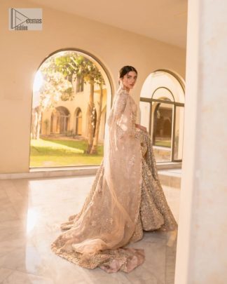 It features a softgalm-inspired look that redefines elegance.  An elegant rhyme to tradition, the attractive and beautiful walima wear lehnga choli creates aesthetical magic with its eye-catching ivory colour. The blouse shines with embellishments and an amalgamation of floral patterns in silver and golden colours. It is further intensified with tilla, dabka, kora, Kundan and the real magic of Zardozi. The boat shape neckline makes this charming. In addition to this, the floral patterns on full sleeves make this masterpiece more lovely. The perfect outfit is paired with a flared lehenga which is heavily ornamented with handsome embroidery. Complete this with an organza dupatta which is adorned with a four-sided embellished border and sprayed with tiny floral motifs and sequins all over to make your day fresh and bright.