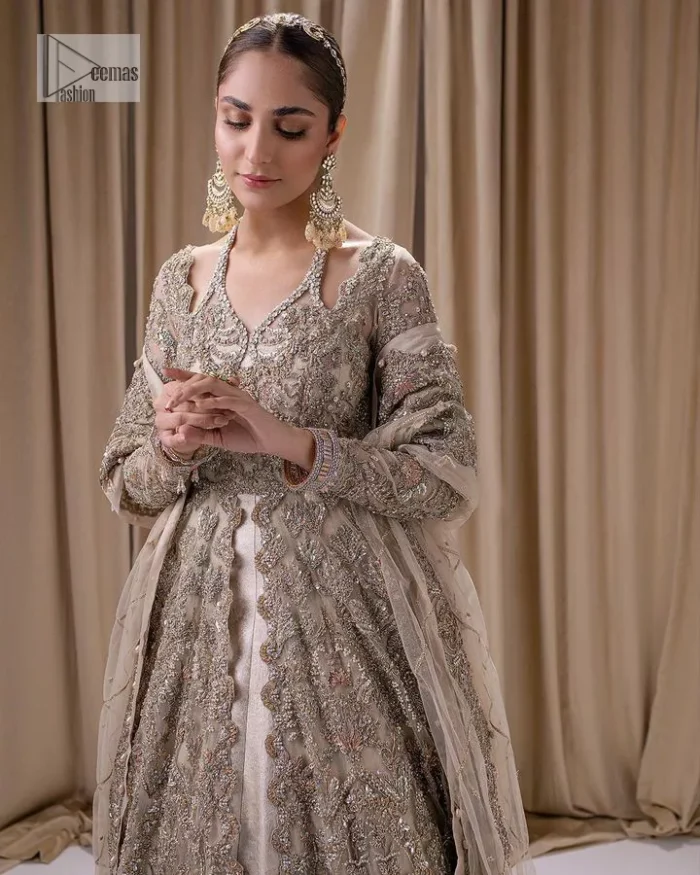 Make a statement with a light fawn article on your nikah day! DeemasFashion presents the light fawn heavy maxi which is embellished with silver embroidery using dabka, tilla, kora, Zardozi, Swarovski, Mukesh, sequin and Kundan. The strap neckline adds a little romanticness to the dress. Further, the floral patterns on full sleeves make this masterpiece modern and unique. It is paired with a  lehenga, embellished with a delicate border. It is styled with a dupatta; its surface is sprayed with sequin and the dupatta is enveloped by a heavily embellished floral border.
