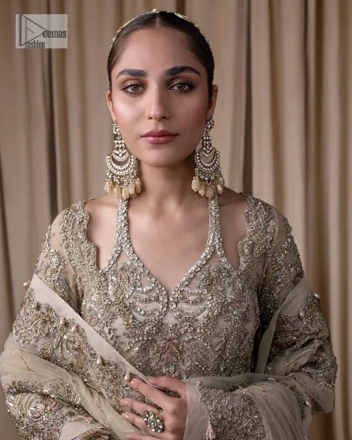 Make a statement with a light fawn article on your nikah day! DeemasFashion presents the light fawn heavy maxi which is embellished with silver embroidery using dabka, tilla, kora, Zardozi, Swarovski, Mukesh, sequin and Kundan. The strap neckline adds a little romanticness to the dress. Further, the floral patterns on full sleeves make this masterpiece modern and unique. It is paired with a  lehenga, embellished with a delicate border. It is styled with a dupatta; its surface is sprayed with sequin and the dupatta is enveloped by a heavily embellished floral border.