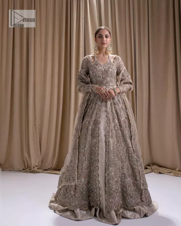 Make a statement with a light fawn article on your nikah day! DeemasFashion presents the light fawn heavy maxi which is embellished with silver embroidery using dabka, tilla, kora, Zardozi, Swarovski, Mukesh, sequin and Kundan. The strap neckline adds a little romanticness to the dress. Further, the floral patterns on full sleeves make this masterpiece modern and unique. It is paired with a  lehenga, embellished with a delicate border. It is styled with a dupatta; its surface is sprayed with sequin and the dupatta is enveloped by a heavily embellished floral border.