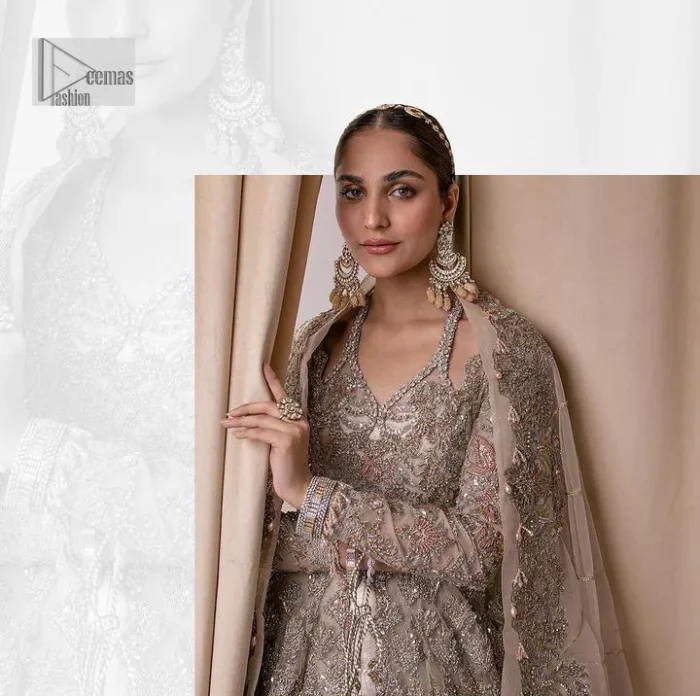 Make a statement with a light fawn article on your nikah day! DeemasFashion presents the light fawn heavy maxi which is embellished with silver embroidery using dabka, tilla, kora, Zardozi, Swarovski, Mukesh, sequin and Kundan. The strap neckline adds a little romanticness to the dress. Further, the floral patterns on full sleeves make this masterpiece modern and unique. It is paired with a  lehenga, embellished with a delicate border. It is styled with a dupatta; its surface is sprayed with sequin and the dupatta is enveloped by a heavily embellished floral border.