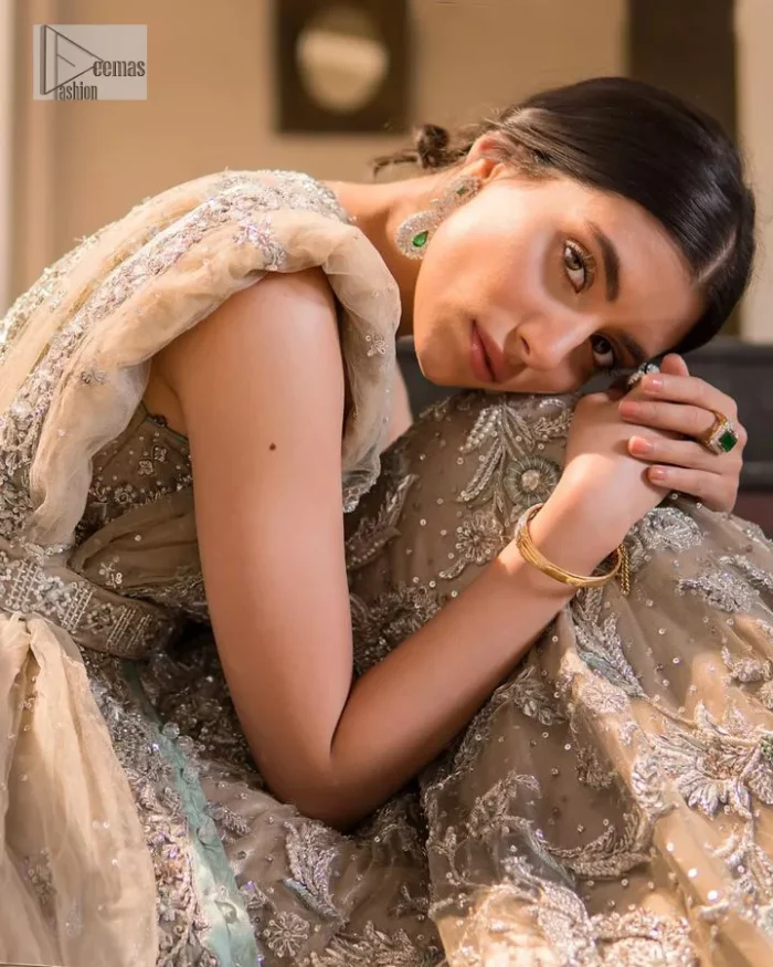 Your wedding vibe. Your wedding mood. Your wedding scent. The light fawn back train heavy maxi and dupatta are hand embellished with straight tilla, dabka, Kundan, Zardozi and kora with running hangings of pearls, crystals, and flat sequins. The sleeveless style of the following back train maxi gives a romantic touch to the whole walima wear. Further, the jewel neckline makes this symbol of beauty. It is paired up with a dupatta framed with a four-sided embellished border with our statement floral pattern and sprayed sequins to make you feel fresh and bold.