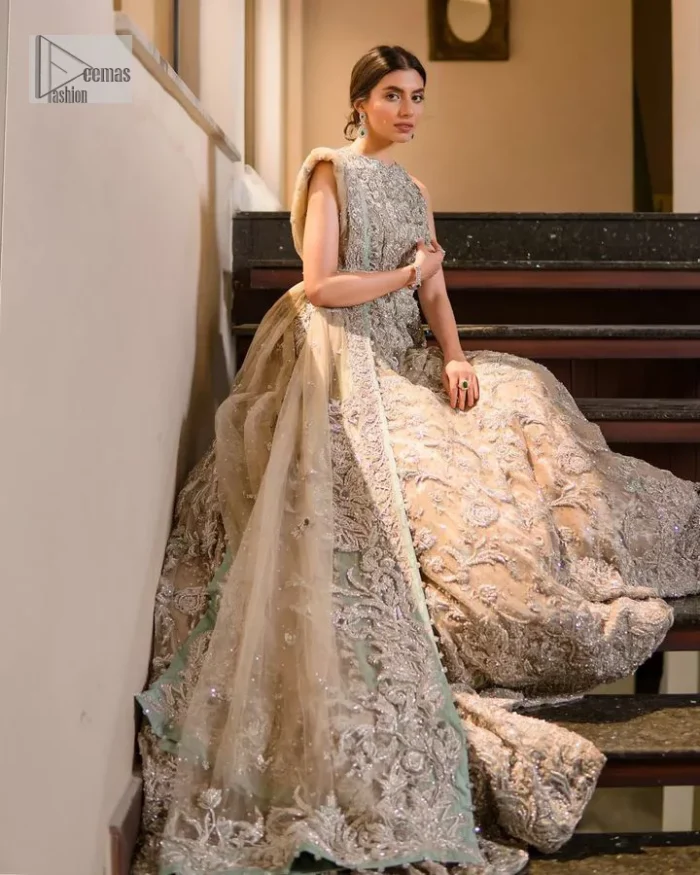 Your wedding vibe. Your wedding mood. Your wedding scent. The light fawn back train heavy maxi and dupatta are hand embellished with straight tilla, dabka, Kundan, Zardozi and kora with running hangings of pearls, crystals, and flat sequins. The sleeveless style of the following back train maxi gives a romantic touch to the whole walima wear. Further, the jewel neckline makes this symbol of beauty. It is paired up with a dupatta framed with a four-sided embellished border with our statement floral pattern and sprayed sequins to make you feel fresh and bold.