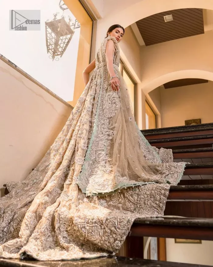 Your wedding vibe. Your wedding mood. Your wedding scent. The light fawn back train heavy maxi and dupatta are hand embellished with straight tilla, dabka, Kundan, Zardozi and kora with running hangings of pearls, crystals, and flat sequins. The sleeveless style of the following back train maxi gives a romantic touch to the whole walima wear. Further, the jewel neckline makes this symbol of beauty. It is paired up with a dupatta framed with a four-sided embellished border with our statement floral pattern and sprayed sequins to make you feel fresh and bold.