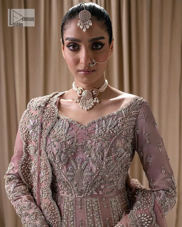 Stand out and stay pink with this nikah wear! The delightful article in pink colour is a traditional masterpiece that will give the gorgeous bride a head-turning look at the wedding. The frock has a sweetheart neckline to make this outfit lovely. It is adorned with silver and golden embroidery which is magnified with tilla, dabka, Koran, Kundan and the details of Zardozi. Further, the combination of tiny and large floral motifs on full sleeves provides a perfect finishing look to this masterpiece. It is paired up with a lehenga in the same colour making it an epitome of beauty and grace. Finish this with a dupatta framed with four-sided embellished scalloped borders and tiny floral motifs all over.