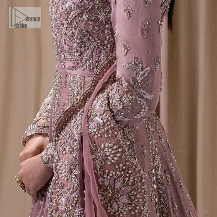 Stand out and stay pink with this nikah wear! The delightful article in pink colour is a traditional masterpiece that will give the gorgeous bride a head-turning look at the wedding. The frock has a sweetheart neckline to make this outfit lovely. It is adorned with silver and golden embroidery which is magnified with tilla, dabka, Koran, Kundan and the details of Zardozi. Further, the combination of tiny and large floral motifs on full sleeves provides a perfect finishing look to this masterpiece. It is paired up with a lehenga in the same colour making it an epitome of beauty and grace. Finish this with a dupatta framed with four-sided embellished scalloped borders and tiny floral motifs all over.