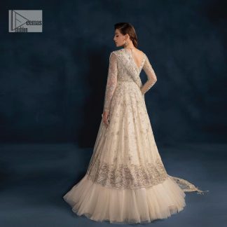 A sophisticated splash of off-white as your nikah outfit! With its round neckline and full sleeves, this outfit has a fine fusion look. Utilizing attractive silver embellishment work to enhance its intricate beauty. Tilla, dabka, kora, Kundan and the details of Zardozi beautifully embellish the elegant frock. It is paired with a flared lehenga to balance the overall look of this charming article. Finish this soft and bold look with a heavily bordered four-sided dupatta with a spray of sequins all over to make your Big day super aesthetic.