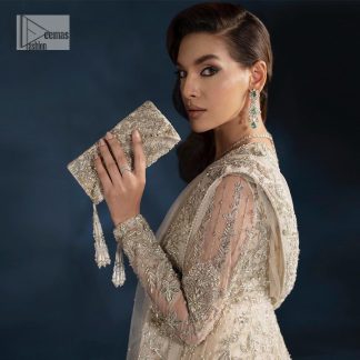 A sophisticated splash of off-white as your nikah outfit! With its round neckline and full sleeves, this outfit has a fine fusion look. Utilizing attractive silver embellishment work to enhance its intricate beauty. Tilla, dabka, kora, Kundan and the details of Zardozi beautifully embellish the elegant frock. It is paired with a flared lehenga to balance the overall look of this charming article. Finish this soft and bold look with a heavily bordered four-sided dupatta with a spray of sequins all over to make your Big day super aesthetic.