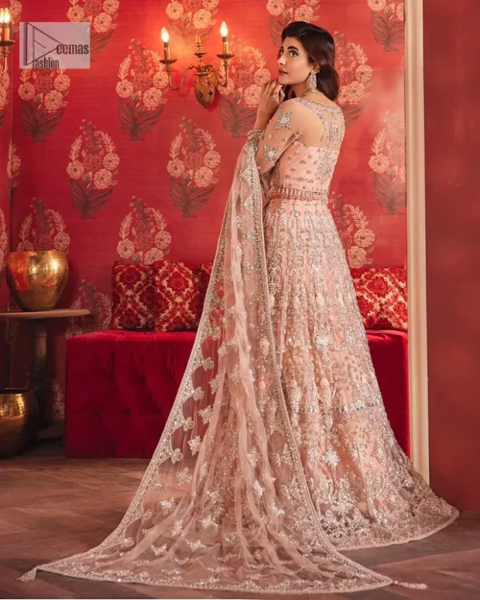 The beautiful outfit comes has an alluring peach colour and is gracefully emblazoned with embroidery. Hand-crafted details of tilla, dabka, kora, Kundan, stones, motifs, and sequins enhance the charm of this outfit. The sweetheart neckline makes this blouse a little more romantic for your walima day. Further, the floral motifs on half sleeves are just a new trend of looming on your day. It is organized with a heavy lehenga. Beaming silver work, floral designs, and lavish details give a perfect finishing look to the masterpiece. Complete this attire with a dupatta framed with a four-sided borders and floral motifs all over.