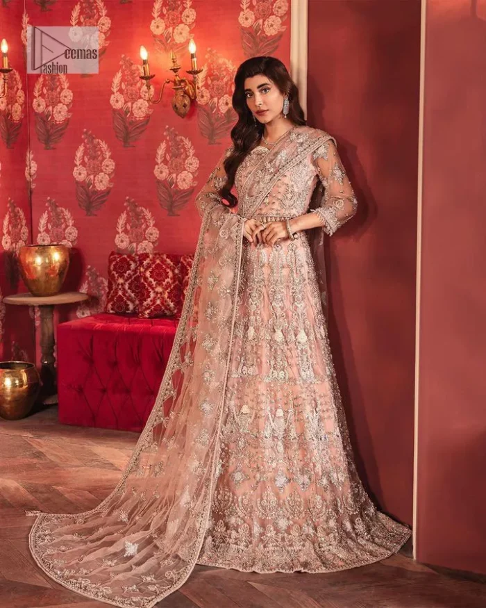 The beautiful outfit comes has an alluring peach colour and is gracefully emblazoned with embroidery. Hand-crafted details of tilla, dabka, kora, Kundan, stones, motifs, and sequins enhance the charm of this outfit. The sweetheart neckline makes this blouse a little more romantic for your walima day. Further, the floral motifs on half sleeves are just a new trend of looming on your day. It is organized with a heavy lehenga. Beaming silver work, floral designs, and lavish details give a perfect finishing look to the masterpiece. Complete this attire with a dupatta framed with a four-sided borders and floral motifs all over.