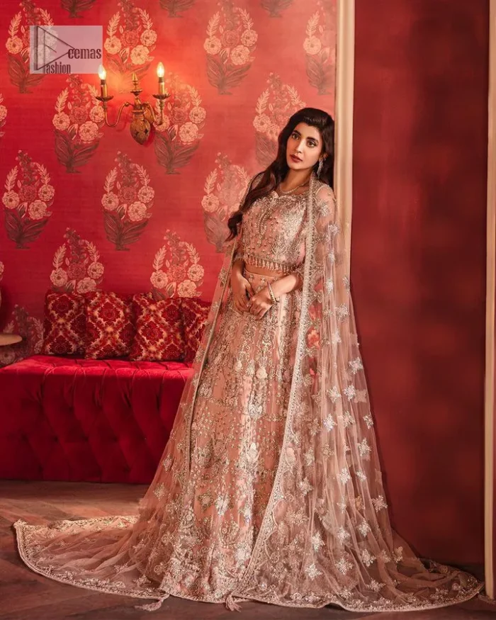 The beautiful outfit comes has an alluring peach colour and is gracefully emblazoned with embroidery. Hand-crafted details of tilla, dabka, kora, Kundan, stones, motifs, and sequins enhance the charm of this outfit. The sweetheart neckline makes this blouse a little more romantic for your walima day. Further, the floral motifs on half sleeves are just a new trend of looming on your day. It is organized with a heavy lehenga. Beaming silver work, floral designs, and lavish details give a perfect finishing look to the masterpiece. Complete this attire with a dupatta framed with a four-sided borders and floral motifs all over.