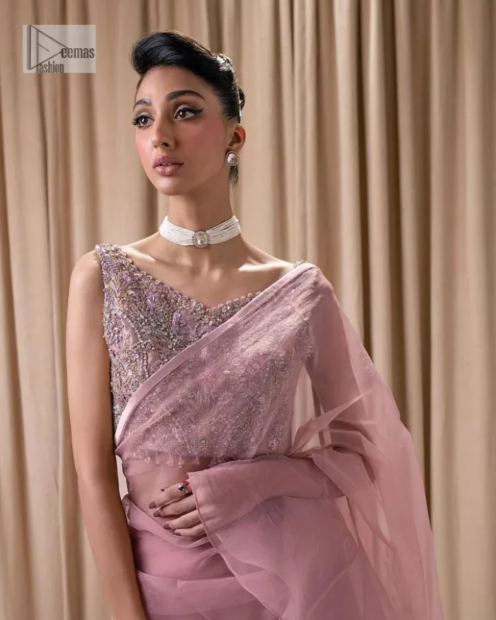 Turn heads in our stunning bridesmaid saree! The beautiful tea pink blouse is adorned with silver and golden embroidery which is intensified with tilla, dabka, kora, Kundan and the details of Zardozi. The V shape neckline provides a perfect finishing look to this masterpiece. In addition to this, the sleeveless style of the following blouse makes this outfit unique and romantic. It is paired up with a frilled saree which is plain just to enhance the beauty of this lovely outfit. 