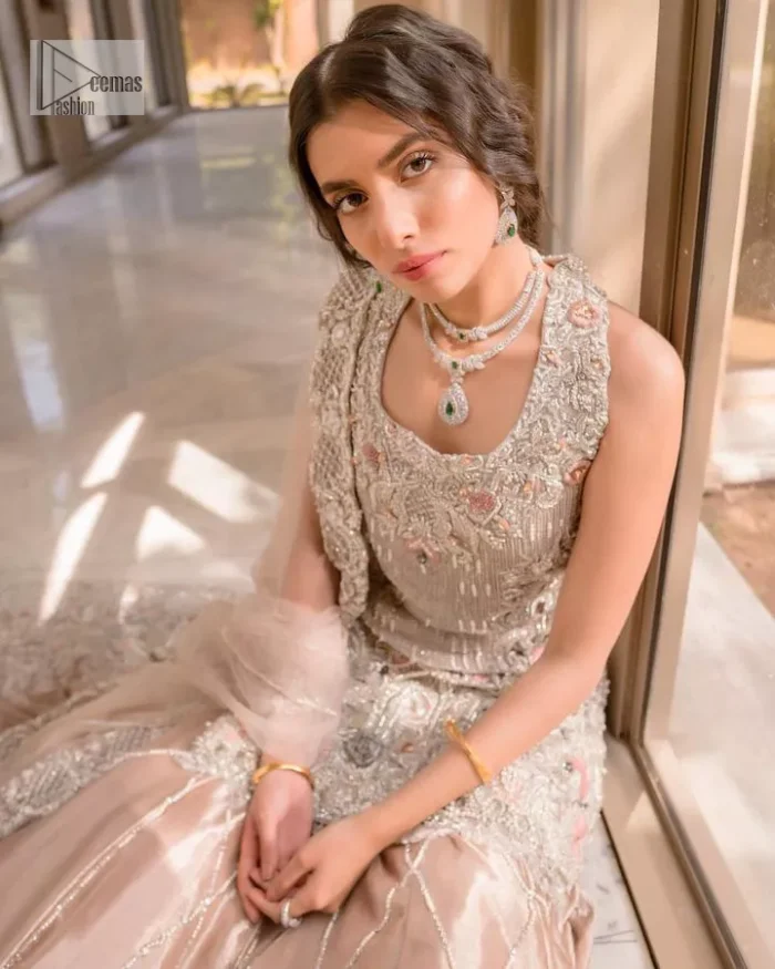 The beauty of idealism is captured with a touch of sparkle. This exclusive rose pink ensemble is beautifully translated on rose pink canvas, which makes this walima outfit stand out in the crowd. This fully embellished article comes with a short shirt lehenga style that gives it a bold look. The round neckline makes this masterpiece a unique cut. The short shirt is adorned with a silver embroidery which involves tilla, dabka, kora, Kundan and the real magic of Zardozi. Further, the sleeveless style of the following short shirt adds charm to the lehenga with heavy border embellishments on it. Carrying out its final contemporary look with a net scalloped dupatta framed with four-sided embellished borders and cross lines all over.
