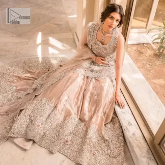 The beauty of idealism is captured with a touch of sparkle. This exclusive rose pink ensemble is beautifully translated on rose pink canvas, which makes this walima outfit stand out in the crowd. This fully embellished article comes with a short shirt lehenga style that gives it a bold look. The round neckline makes this masterpiece a unique cut. The short shirt is adorned with a silver embroidery which involves tilla, dabka, kora, Kundan and the real magic of Zardozi. Further, the sleeveless style of the following short shirt adds charm to the lehenga with heavy border embellishments on it. Carrying out its final contemporary look with a net scalloped dupatta framed with four-sided embellished borders and cross lines all over.