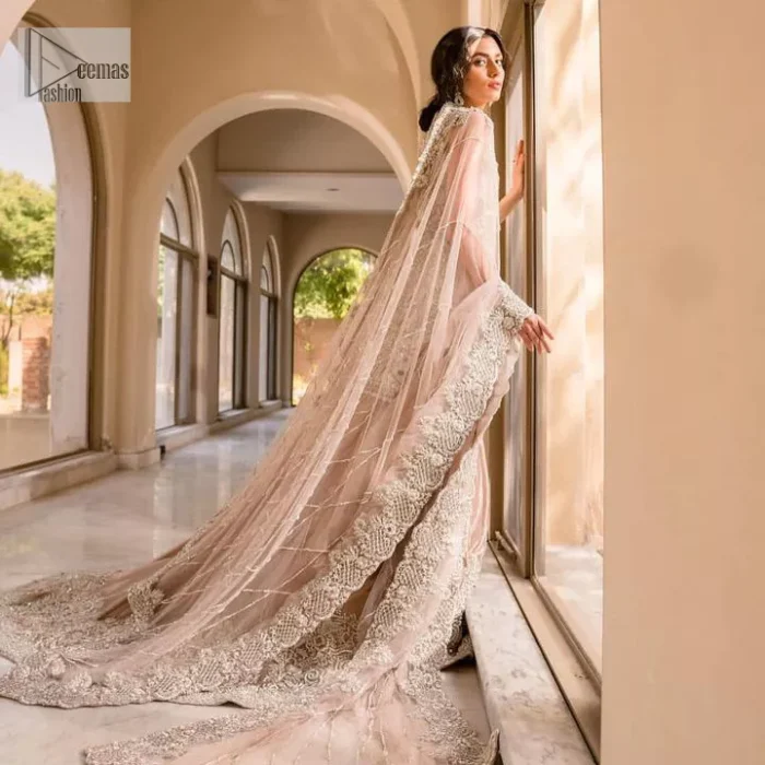 The beauty of idealism is captured with a touch of sparkle. This exclusive rose pink ensemble is beautifully translated on rose pink canvas, which makes this walima outfit stand out in the crowd. This fully embellished article comes with a short shirt lehenga style that gives it a bold look. The round neckline makes this masterpiece a unique cut. The short shirt is adorned with a silver embroidery which involves tilla, dabka, kora, Kundan and the real magic of Zardozi. Further, the sleeveless style of the following short shirt adds charm to the lehenga with heavy border embellishments on it. Carrying out its final contemporary look with a net scalloped dupatta framed with four-sided embellished borders and cross lines all over.