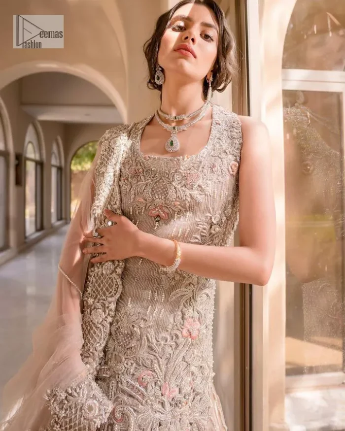 The beauty of idealism is captured with a touch of sparkle. This exclusive rose pink ensemble is beautifully translated on rose pink canvas, which makes this walima outfit stand out in the crowd. This fully embellished article comes with a short shirt lehenga style that gives it a bold look. The round neckline makes this masterpiece a unique cut. The short shirt is adorned with a silver embroidery which involves tilla, dabka, kora, Kundan and the real magic of Zardozi. Further, the sleeveless style of the following short shirt adds charm to the lehenga with heavy border embellishments on it. Carrying out its final contemporary look with a net scalloped dupatta framed with four-sided embellished borders and cross lines all over.
