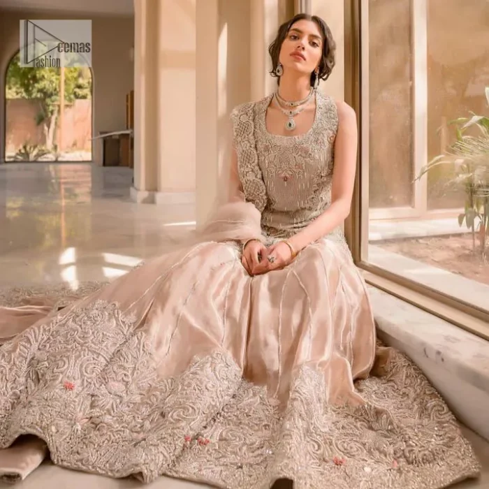 The beauty of idealism is captured with a touch of sparkle. This exclusive rose pink ensemble is beautifully translated on rose pink canvas, which makes this walima outfit stand out in the crowd. This fully embellished article comes with a short shirt lehenga style that gives it a bold look. The round neckline makes this masterpiece a unique cut. The short shirt is adorned with a silver embroidery which involves tilla, dabka, kora, Kundan and the real magic of Zardozi. Further, the sleeveless style of the following short shirt adds charm to the lehenga with heavy border embellishments on it. Carrying out its final contemporary look with a net scalloped dupatta framed with four-sided embellished borders and cross lines all over.