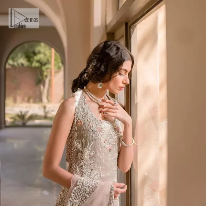The beauty of idealism is captured with a touch of sparkle. This exclusive rose pink ensemble is beautifully translated on rose pink canvas, which makes this walima outfit stand out in the crowd. This fully embellished article comes with a short shirt lehenga style that gives it a bold look. The round neckline makes this masterpiece a unique cut. The short shirt is adorned with a silver embroidery which involves tilla, dabka, kora, Kundan and the real magic of Zardozi. Further, the sleeveless style of the following short shirt adds charm to the lehenga with heavy border embellishments on it. Carrying out its final contemporary look with a net scalloped dupatta framed with four-sided embellished borders and cross lines all over.
