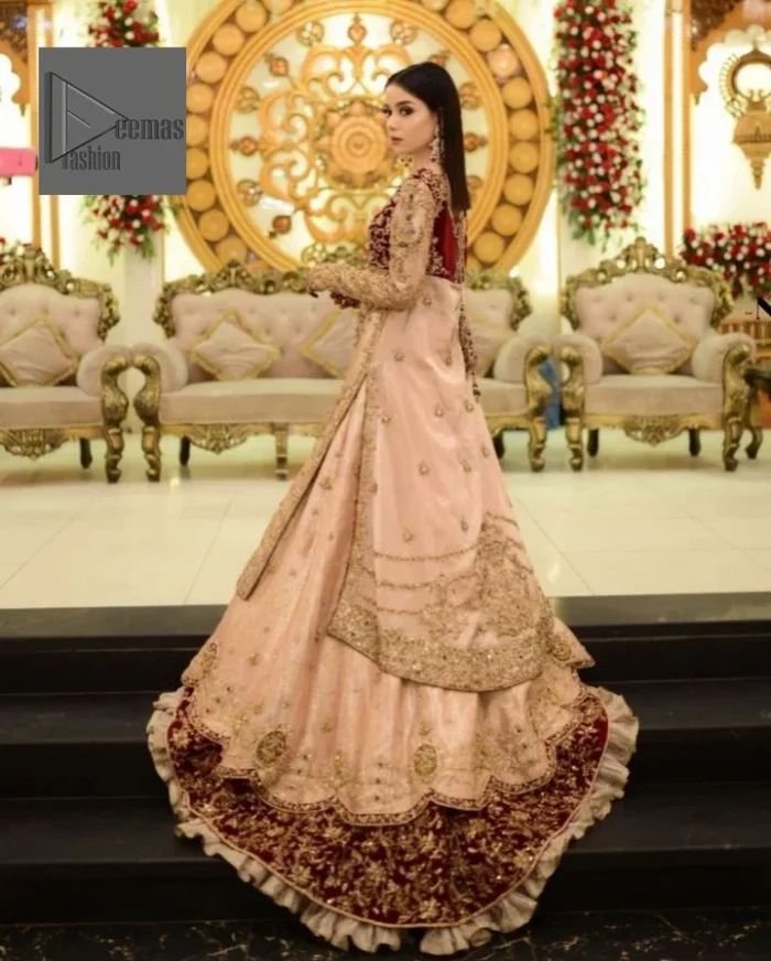 Your words about your special day is expertly written in this beautiful dress. This ivory front open gown is the picture of elegance and majesty. Silver dabka, pearls, tilla, kora, Kundan, zardozi, and the true magic of beads are used to embellish the stunning garment. Golden embroidery on it makes it stand out. The V-shaped neckline of the dress elevates this ensemble. Moreover, full sleeves are embellished with the lovely embroidery. Pairing the richly embroidered ivory gown with a set of simple frilled lehenga and inner frock would look stunning. To achieve professional magic, it is set up with a dupatta that is bordered with four-sided borders and spray of sequins all over.