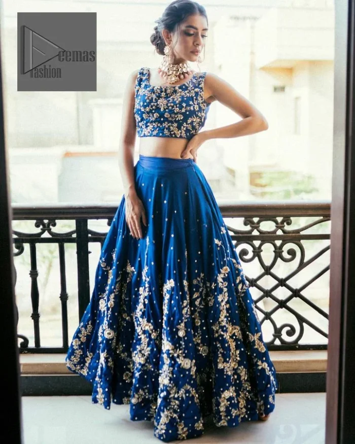 The Royal blue blouse is adorned with silver embroidery, making it a head-turning masterpiece. Moreover, the square neckline is fully embellished with tilla, dabka, kora, Kundan, and pearls, lending it a magical appearance. This Party outfit from DeemasFashion is a stunning masterpiece that captures everyone's heart with its charm and elegance upon very first glance.