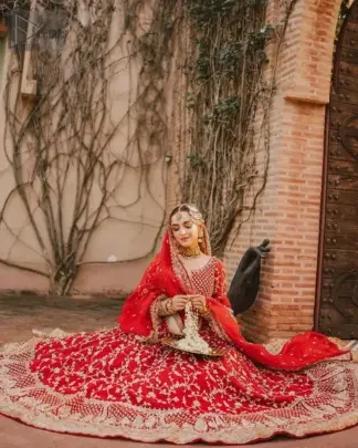 Step into your reception with confidence and poise in our exceptional red reception outfit, a true embodiment of individuality. This unique dress is a masterpiece of design that involves light golden and bosky shades of embroidery having tilla, dabka, kora, Kundan, and Zardozi, crafted to capture the essence of your special day with unparalleled style.