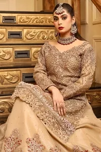 The antique embroidery delicately adorns the beige shirt, while the boat-shaped neckline and full sleeves create a refined, graceful silhouette.