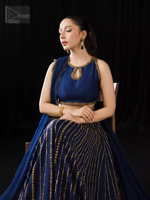 The sleeveless blouse choli glows like hidden fire when it gleams under the golden embroidery of the halterneck cut.